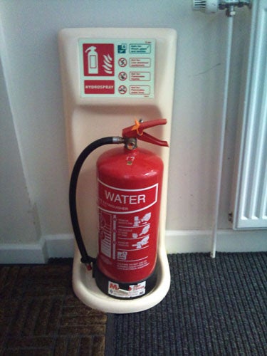 Red water fire extinguisher mounted on wall.