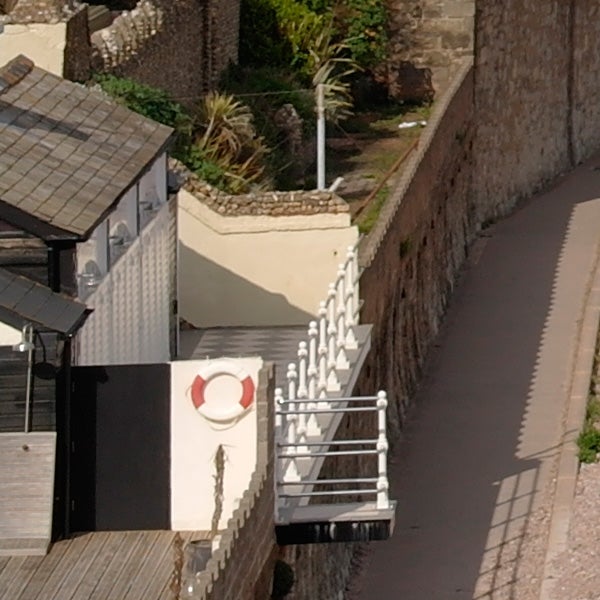High-angle view of a coastal walkway and building terrace.