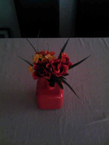 Vase with red and yellow flowers on a table.