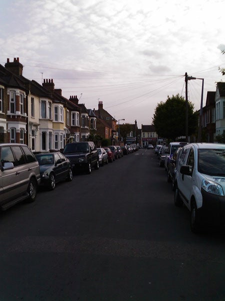Residential street with parked cars and overcast sky.