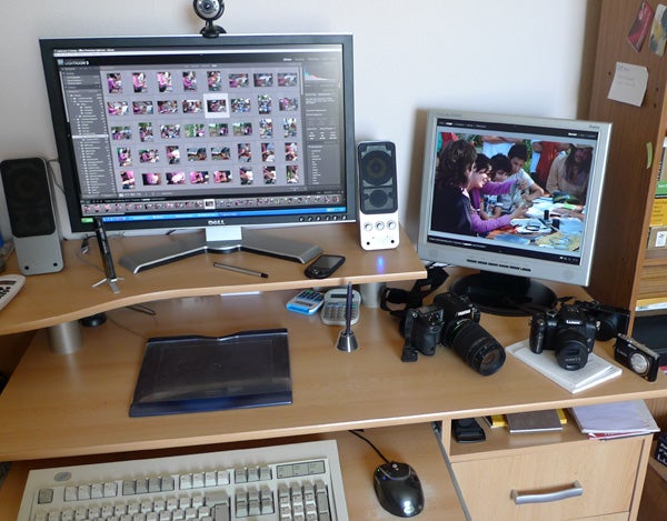 Workspace with Adobe Lightroom on dual monitor setup and cameras.