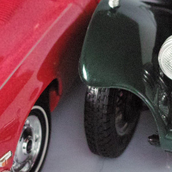 Close-up of red and green vintage cars' fenders and wheels.