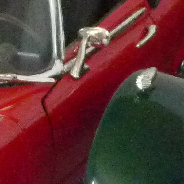 Close-up of a classic red car door and wing mirror.