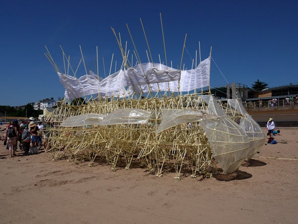 Art installation on the beach with people observing.