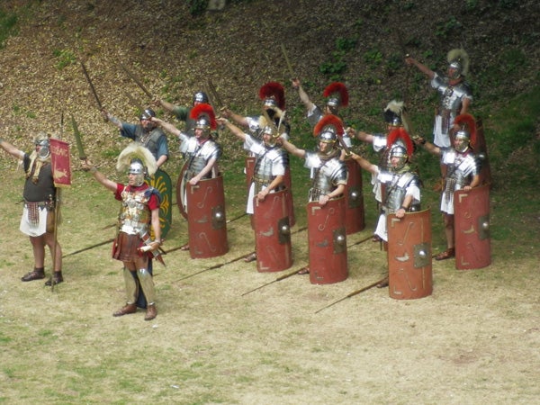 Reenactors dressed as Roman soldiers in formation.