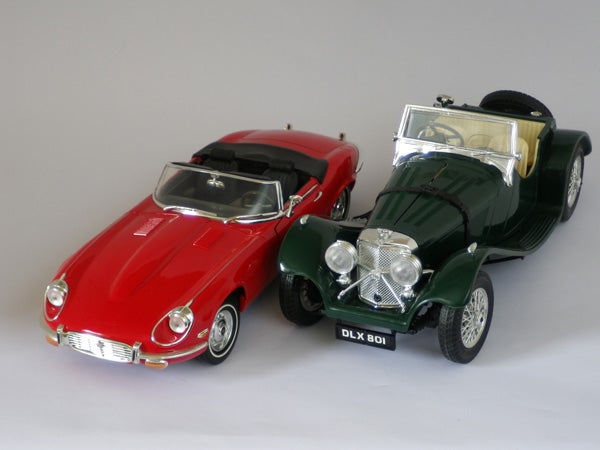 Two model cars, a red convertible and a green classic roadster.