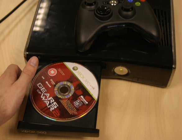 Hand inserting Gears of War 2 disc into Xbox 360 console.