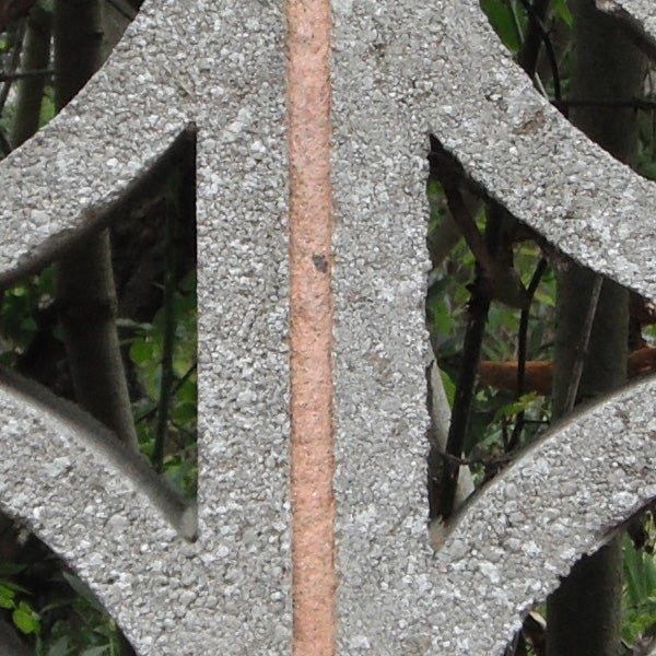 Close-up of rusted metal rod amidst gray geometric shapes.