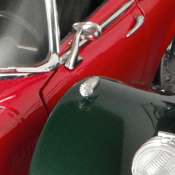 Close-up of a red vintage car's shiny chrome detail.