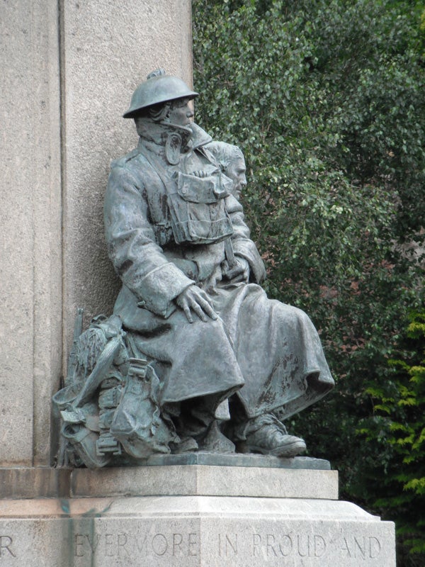 Statue of a soldier sitting with a helmet and gear.