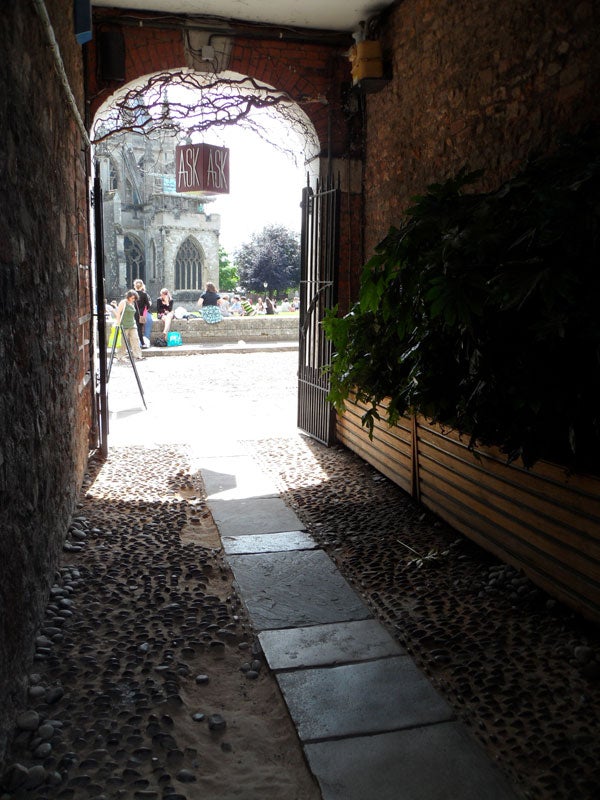 View through an archway with a glimpse of a church and people outside.