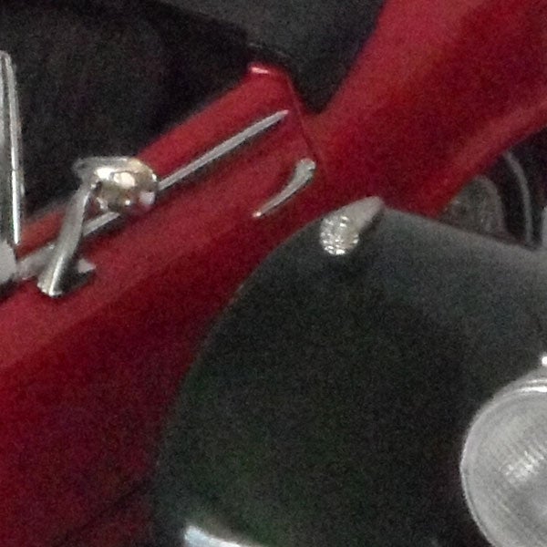 Close-up of a red metallic surface with reflections and screws.