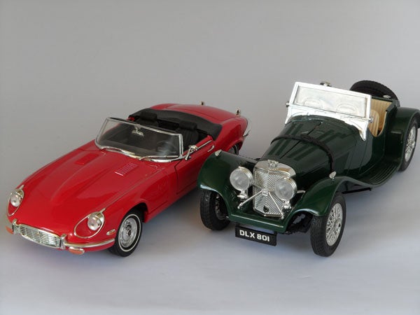 Two vintage model cars on a grey background.