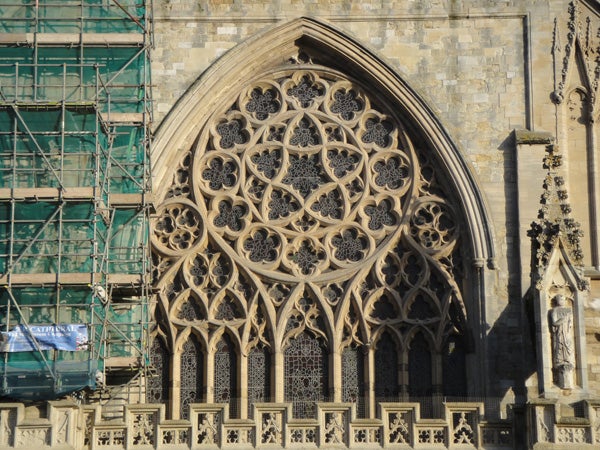 Intricate cathedral rose window and stonework with scaffolding.