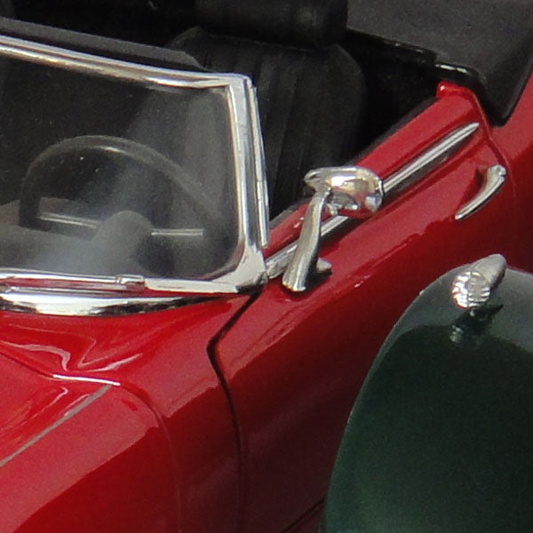 Close-up of a red vintage car door and side mirror.