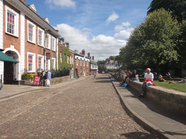 Photo captured with Sony Cyber-shot DSC-TX5 showing a cobbled street and people relaxing.