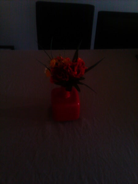 Vase with flowers on a table in dim lighting.
