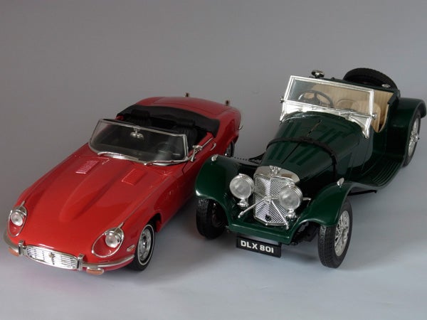 Photo of two model cars, red Jaguar E-Type and green vintage car.