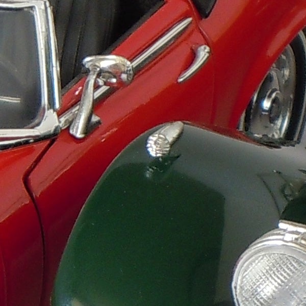 Close-up of a red vintage car's door and chrome handle
