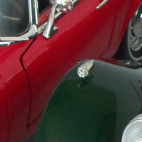 Close-up of a vintage red car's side and headlight.