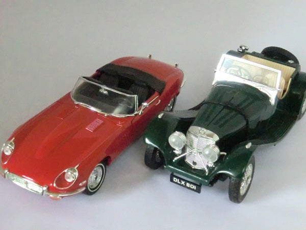 Red and green vintage model cars on a gray surface.