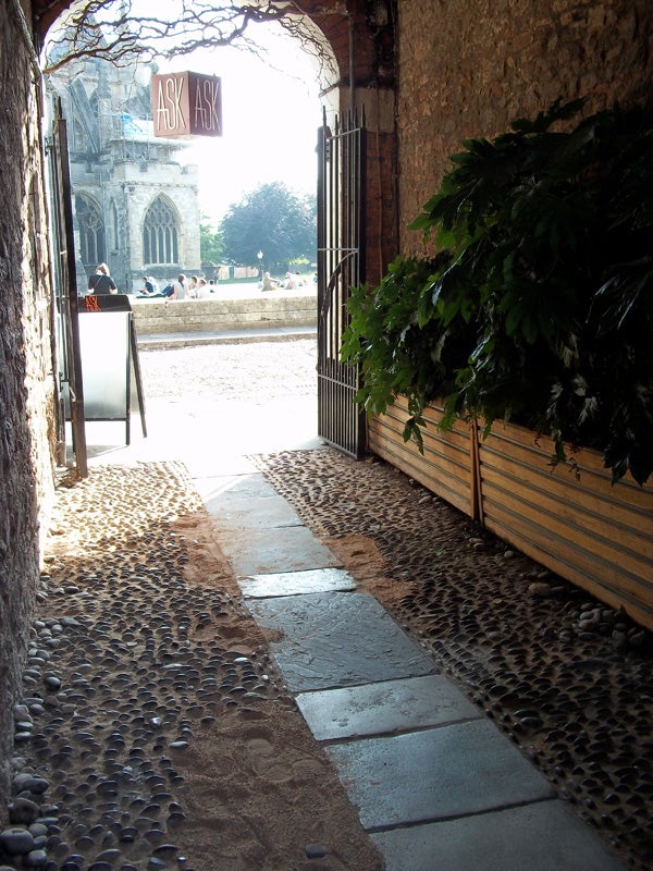 Photo of a cobblestone path leading to an open gate