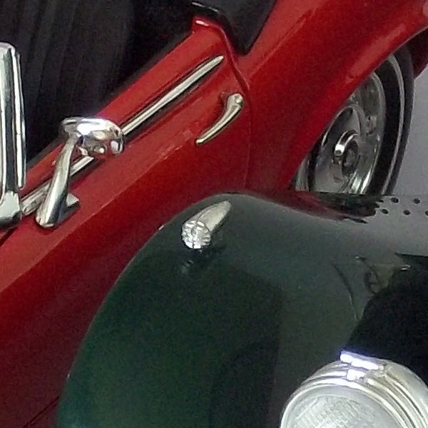 Close-up of a classic red car's shiny chrome details.