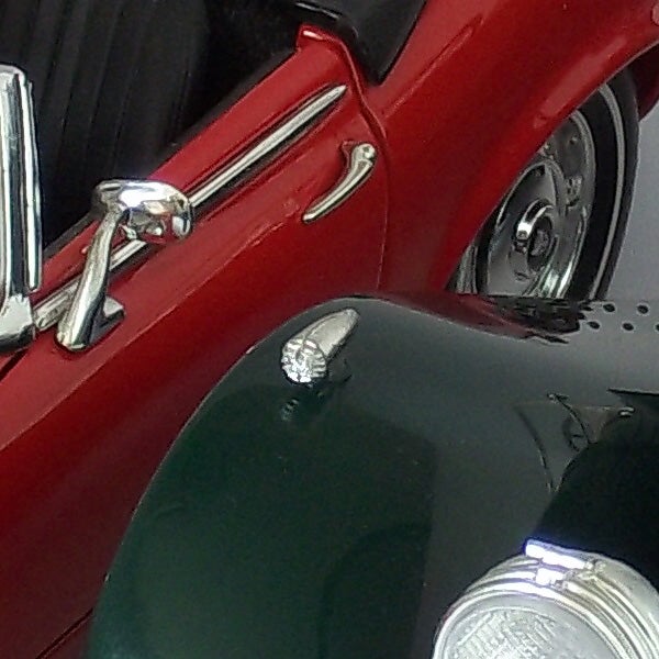 Close-up of a vintage car's shiny red and black details.