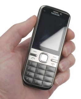 Hand holding a Nokia C5 mobile phone.