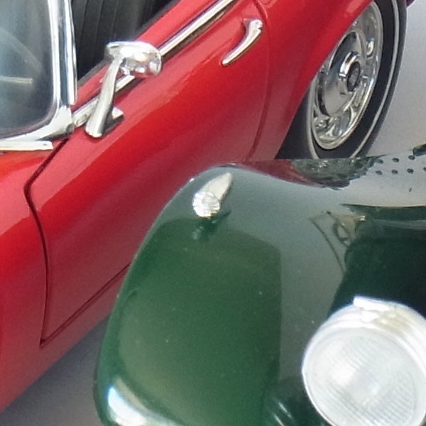 Close-up of vintage red and green cars with reflective surfaces