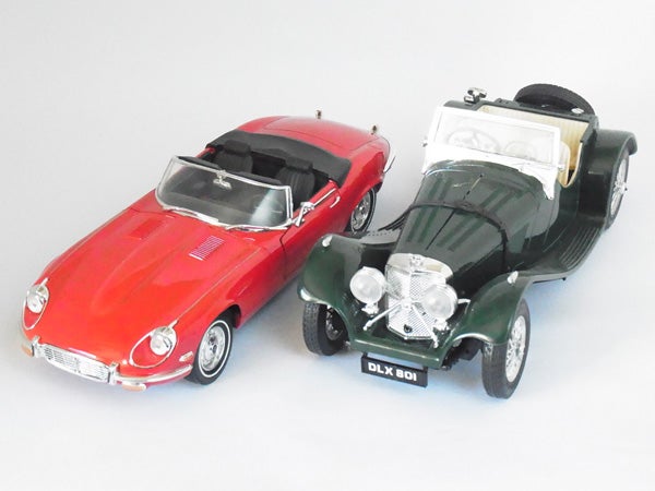 Two model cars, red and green, on a white background.