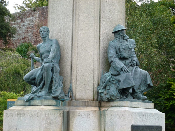 Statues at a war memorial with inscriptions below