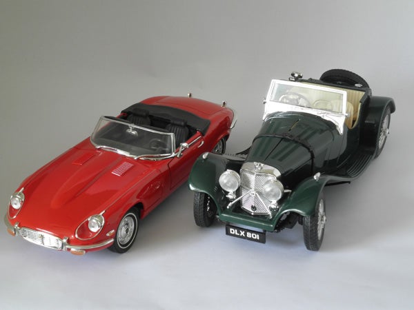 Two vintage model cars on a gray background.