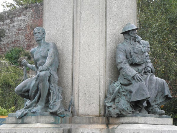 Bronze statues of a sailor and a soldier at a memorial.