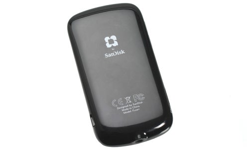 SanDisk Sansa Fuze+ MP3 player lying on a white surface.
