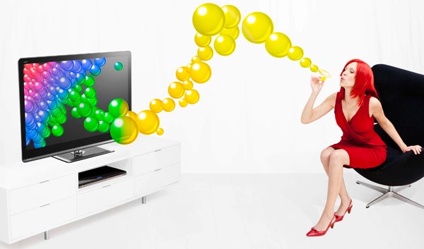 Woman blowing colorful bubbles towards Sharp Aquos TV.