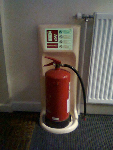 Fire extinguisher mounted on wall next to sign