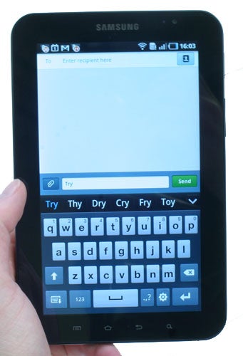 Hand holding a Samsung Galaxy Tab with keyboard on screen.