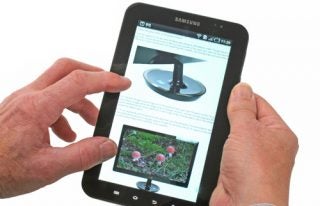 Hands holding a Samsung Galaxy Tab displaying content.