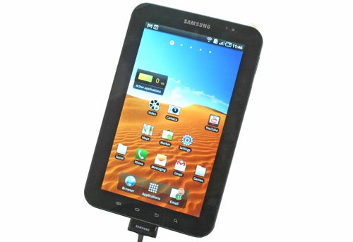 Samsung Galaxy Tab on charge displaying home screen.