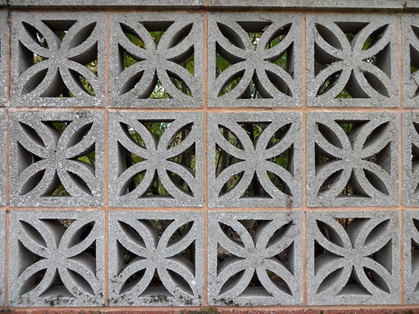 Decorative concrete block wall pattern with foliage behind