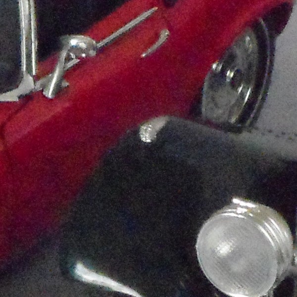 Close-up of a red vintage car and headlight.