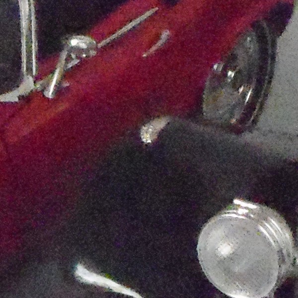 Close-up of a red car's front side, low-resolution image.