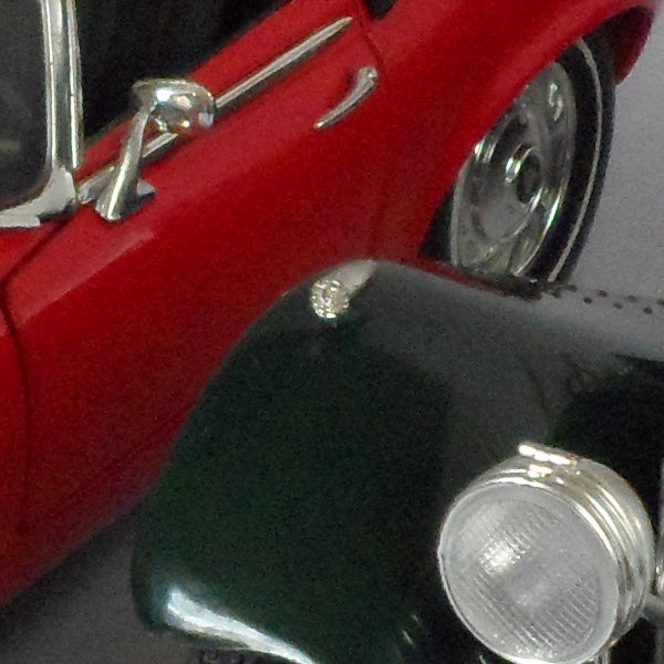 Close-up of a classic red model car's left side.