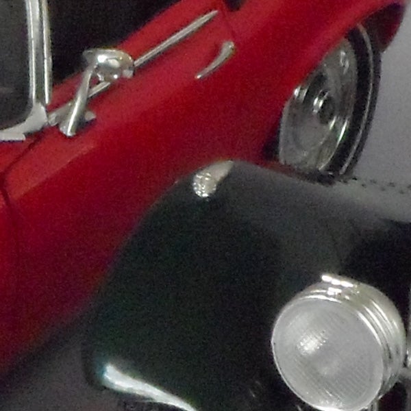 Close-up of classic red car captured with Samsung PL150 camera.