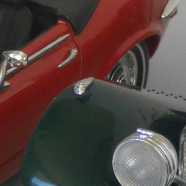 Close-up of a camera reflecting a red car.