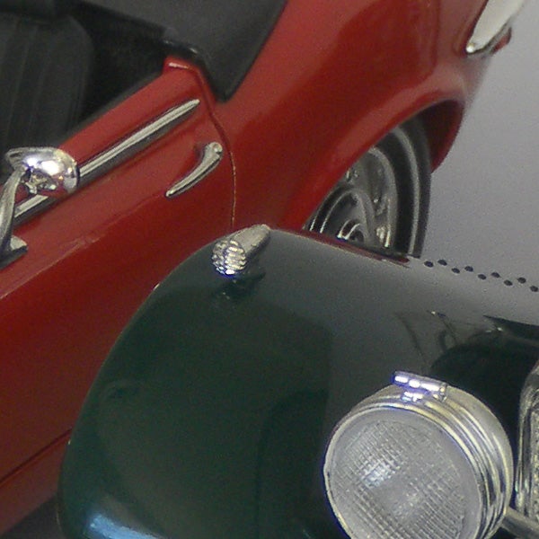 Close-up of vintage car model with red body and chrome details.