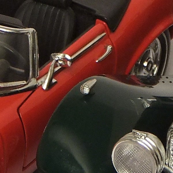 Close-up of a red toy car and a camera lens reflection.