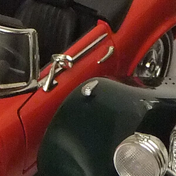 Close-up of a red toy car and a black camera.
