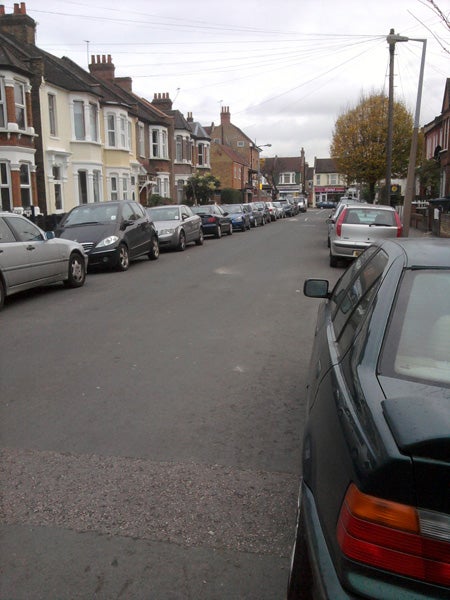 Image showing a street lined with parked cars.